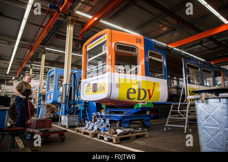 Wuppertal, Germania. 13 Ago, 2015. Un uomo lavora su un carrello nell'officina della stazione ferroviaria di sospensione situato in corrispondenza della sua stazione terminale in Wuppertal, Germania, 13 agosto 2015. Wuppertal's'impresa di pubblica utilità WSW darà via tre carrelli della sua ben nota stazione per libero, con un ulteriore 21 dagli anni settanta per essere venduto per 5.000 euro l'anno prossimo quando la quarta generazione della ferrovia è programmata per avviare l'attività. Foto: Maja Hitij/dpa/Alamy Live News Foto Stock