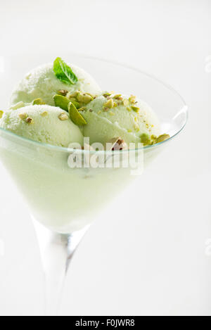 Un cucchiaio di pistacchio gelato con pistacchi in vetro vicino. Foto Stock