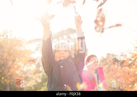 Entusiastico ragazzo giocando in foglie di autunno Foto Stock