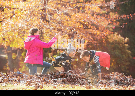 Ragazzo e ragazza che gioca in foglie di autunno Foto Stock