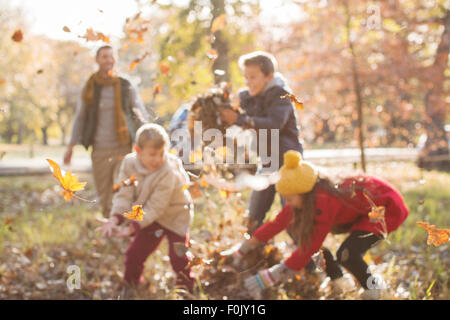 Famiglia giocando in foglie di autunno a park Foto Stock