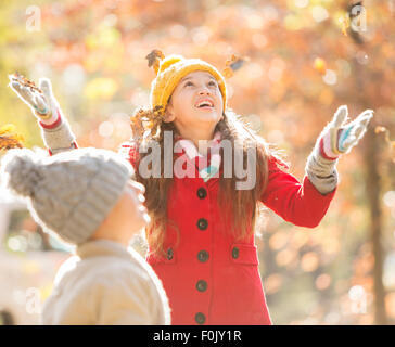 Ragazza gettando le foglie di autunno Foto Stock