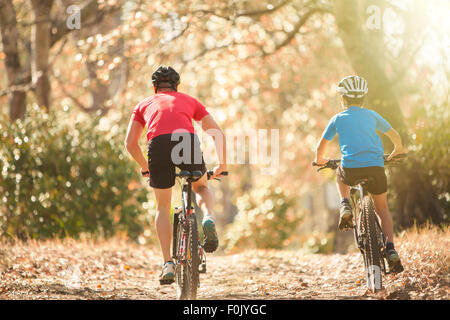 Padre e figlio in mountain bike sul percorso nel bosco Foto Stock