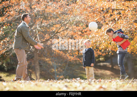 Padre e figli che giocano a calcio in autunno park Foto Stock