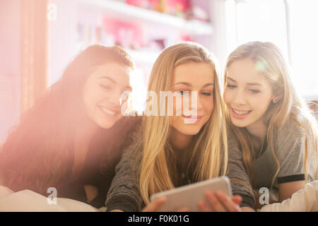 Le ragazze adolescenti sms con il telefono cellulare sul letto Foto Stock