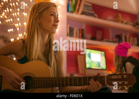 Ragazza adolescente a suonare la chitarra in camera da letto Foto Stock