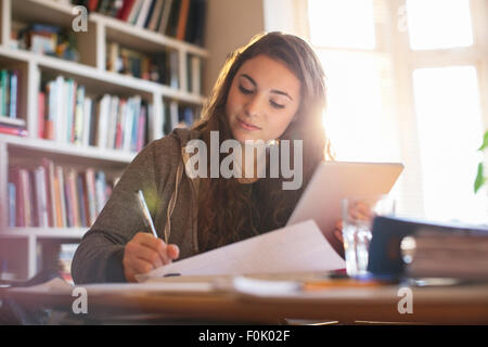 Ragazza adolescente con tavoletta digitale studiare alla scrivania Foto Stock
