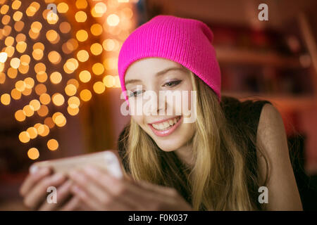 Ragazza adolescente in rosa beanie texting con un telefono cellulare Foto Stock