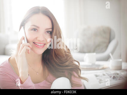Donna che parla al cellulare in salotto Foto Stock