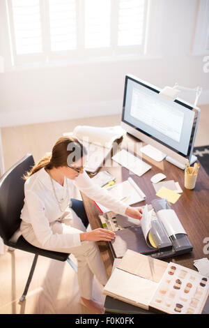 Interior designer esaminando campioni di tappeto a scrivania Foto Stock