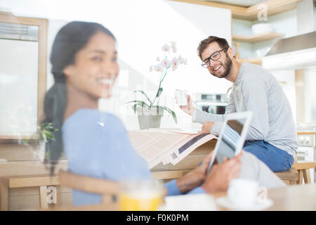 Paio di relax con tavoletta digitale, quotidiano e macchina per caffè Foto Stock