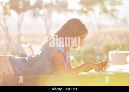 La donna posa con tavoletta digitale sul patio soleggiato Foto Stock