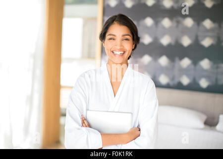 Ritratto di donna sorridente in accappatoio holding tavoletta digitale Foto Stock