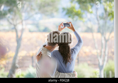 Giovane tenendo selfie con la fotocamera del telefono sul patio Foto Stock