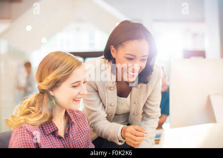 Sorridente imprenditrice utilizzando computer in ufficio soleggiato Foto Stock