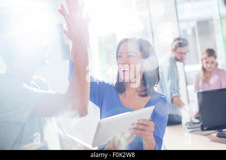 Attività creativa di persone ad alta fiving con tavoletta digitale Foto Stock