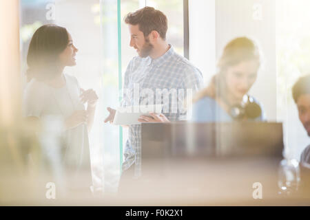 La gente di affari con tavoletta digitale parlando in ufficio Foto Stock