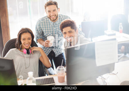 Ritratto sorridente azienda creativa di persone con caffè e cuffie in ufficio Foto Stock