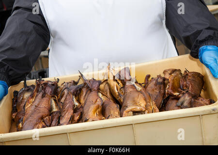 Donna che mantiene vassoio. Eglefino cotto pesci Smokies, affumicati conserve di specialità a base di frutti di mare, ad Arbroath Mare Fest, a nord-est della Scozia, Regno Unito Foto Stock