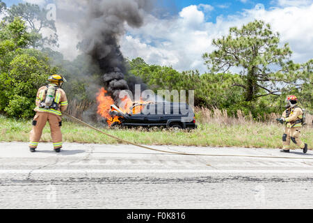 Vigile del fuoco mettendo fuori la macchina fuoco sul lato dell'autostrada Foto Stock