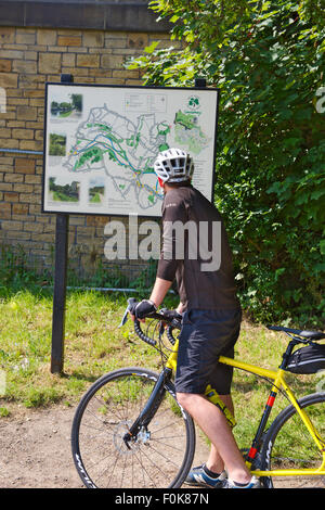 Ciclista controllo mappa di localizzazione lungo Leeds e Liverpool canal, West Yorkshire, Regno Unito Foto Stock