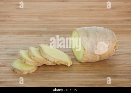 Close-up di pezzo e fette di zenzero fresco su un tagliere di legno. Foto Stock
