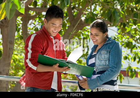 Due senior sorridente teenage agli studenti di confrontare le note di studio al di fuori nel giardino della scuola campus parco giochi Foto Stock