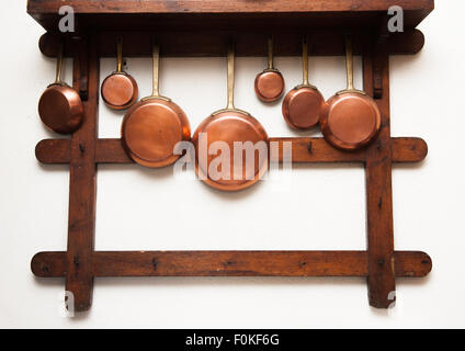 Gruppo di vintage pentole in rame, diverse dimensioni, appeso sul ripiano di legno in cucina Foto Stock