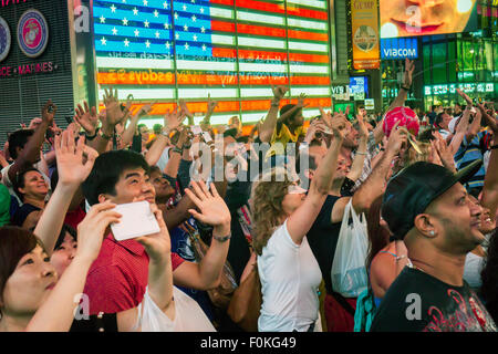 Una mandria di turisti sta sventolando a se stessi su uno degli schermi LED giganteschi in Times Square a New York martedì, 11 agosto 2015. (© Richard B. Levine) Foto Stock