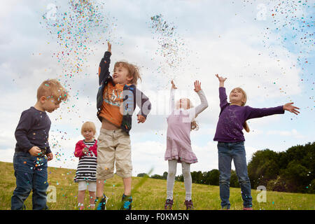 Cinque bambini piccoli gettando coriandoli su un prato Foto Stock