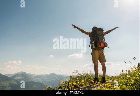 Austria, Tirolo, Tannheimer Tal, giovane uomo in piedi sul sentiero di montagna con le braccia aperte Foto Stock