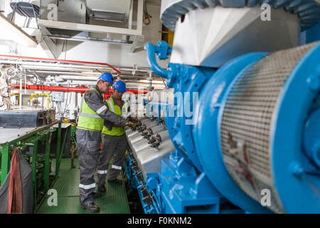 Personale che lavora nella sala del motore su una nave Foto Stock