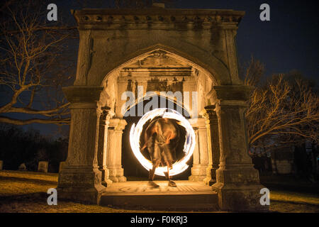 Uno studente di college gira e gioca il fuoco nel cimitero di Oakwood a Syracuse, New York. Foto Stock