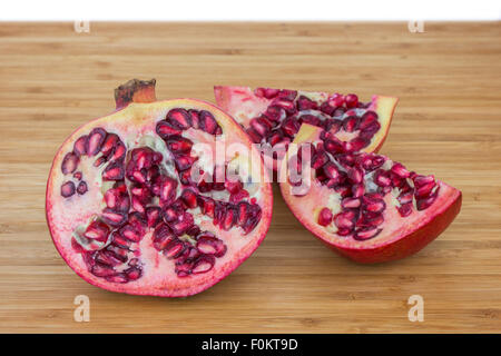 Close-up di un maturo Melograno (Punica granatum) tagliato a metà e split su un tagliere di legno. Foto Stock