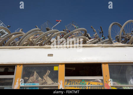 Vecchia scuola bus con carichi di biciclette sul tetto contro un cielo blu. Foto Stock