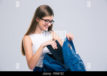 Ritratto di un adolescente di sesso femminile in bicchieri cercando qualcosa nello zaino isolato su uno sfondo bianco Foto Stock