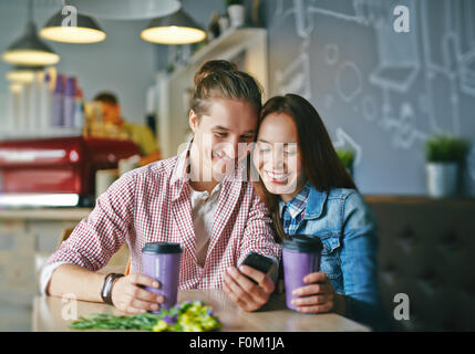 Date affettuoso con il cellulare in seduta cafe Foto Stock