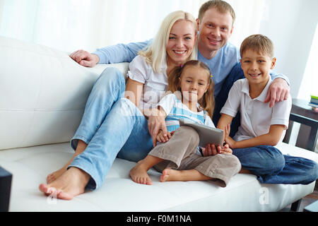Famiglia di quattro persone in posa sul divano Foto Stock