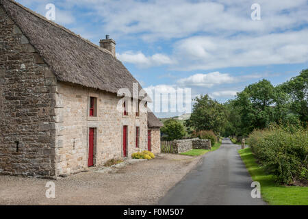 Un pittoresco inglese cottage in pietra con un tetto di paglia Foto Stock