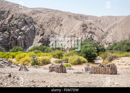 Stile di vita angolana e paesaggio: abbandonata la struttura di legno capanne di fango in robusto, deserto arido terreno, Angola meridionale vicino al confine con la Namibia Foto Stock