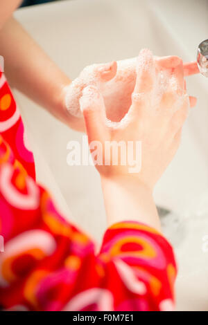 Close up di un po' di ragazze le mani con sapone liquido. Ella sta lavando le mani in un bagno. Foto Stock