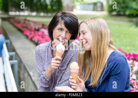 Due amiche ridere insieme e mangiare il gelato Foto Stock