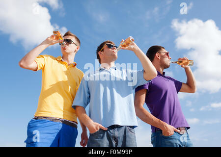 Happy amici con bottiglie di birra sulla spiaggia Foto Stock