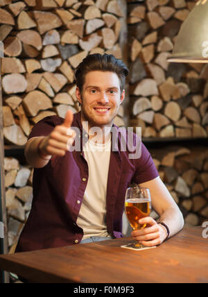 Uomo felice con la birra che mostra i pollici fino al bar Foto Stock