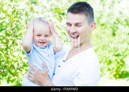 Affascinante caucasian baby boy con il padre nel giardino elevato la chiave Foto Stock