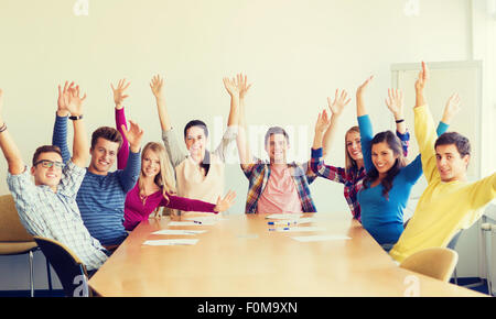 Gruppo di studenti sorridente alzando le mani in office Foto Stock