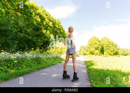 Felice giovane donna in pattini in sella all'aperto Foto Stock