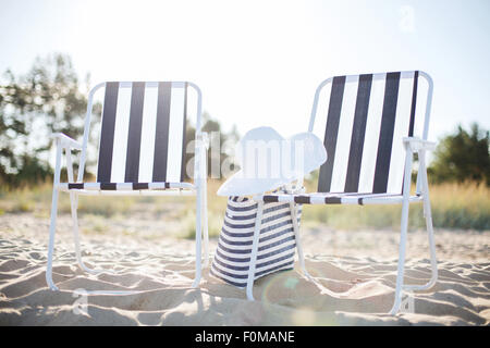 Spiaggia di due saloni con borsa da spiaggia e cappello bianco Foto Stock