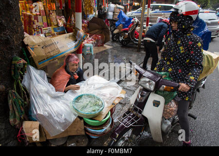Povero venditore ambulante la vendita di frutta e verdura in Hanoi. Foto Stock