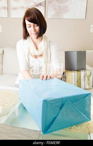 Giovane donna imballaggio presenta nel suo soggiorno Foto Stock